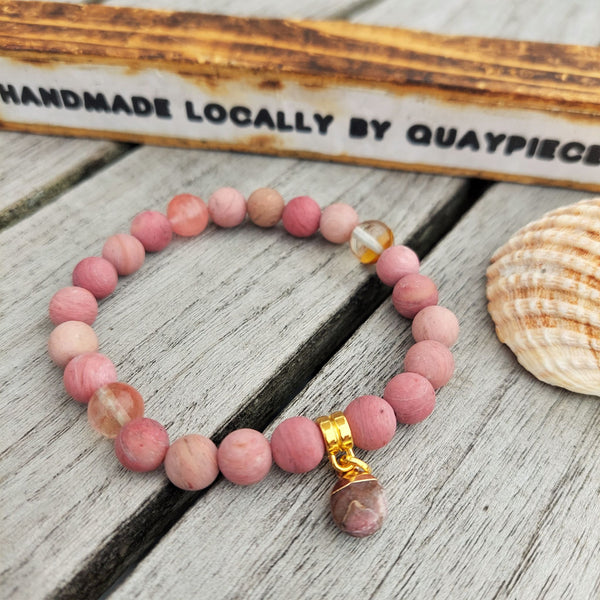 8mm Deep Pink Matt Rhodonite stone bead bracelet with gorgeous gold plated charm  Elasticated, so will fit most adult wrists (measuring 71/2 in/19cm)  Lovely gift for friends or family  **Presented in lovely Kraft paper gift box with reusable organza pouch**