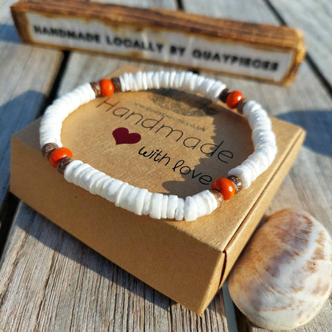 Beach vibes with this super cute stretch beach anklet, handmade with white puka shell discs, coconut &amp; wood/calcite beads.  Choose from Orange or Blue  Elasticated Length - 23cm/9ins&nbsp;  Cool little gift for any surf chick!