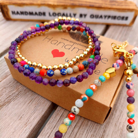This stunning set of 3 handcrafted Beaded Bracelets features unique designs, including one with 4mm faceted purple stone beads, another with 4mm gold plated beads, and a third with 4mm mixed colour jasper beads. Each bracelet is elasticated for a comfortable fit on most adult wrists (7.5 in/19cm-they are designed to fit snugly) They make the perfect accessory for any summer outfit! Plus, they come in a lovely Kraft paper gift box with a reusable organza pouch.