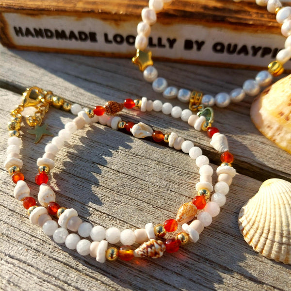 Add some ocean vibes to your look with this handmade necklace of white jade, gold plated and amber agate beads, accompanied by shell discs and fun spiral shells. The gold plated fastenings and clasp with extension chain, adorned with star and shell charms, make it just the right length at 40cm (42cm with extension chain). Wear it alone for a beachy look or stack it with your other favourite accessories! Ocean fun, ready to be worn!
