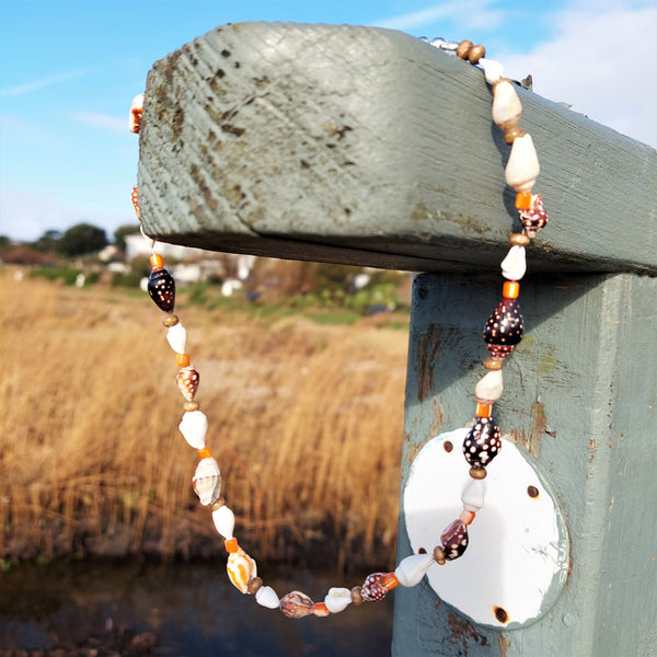 Dainty handmade natural shell, orange shell & wood beaded surf style choker necklace Approximately 10mm coconut brown spiral shells & made with love charm The necklace has sterling silver plated fastenings & lobster clasp with extension chain to adjust the length Length - 40cm extends to 44cm Cute little gift for any Surfer chick! **Presented in lovely Kraft paper gift box with reusable organza pouch** **To keep your quaypieces looking great, always take me off before showering or swimming**
